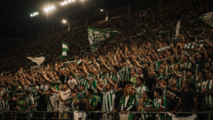 Afición y jugadores del Betis celebrando bajo luces de estadio en una noche europea.
